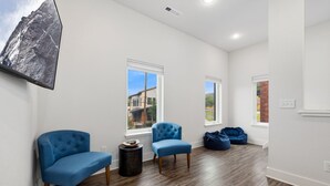 A room with two blue chairs, a round table, and two windows with views of buildings. - Razorblock North - 1 mi from DT - 3 blocks to UofA (Fayetteville)