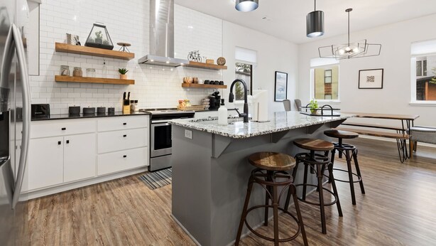 A modern kitchen with white cabinets, a central island with stools, pendant lighting, and a view to the dining area. - Razorblock North - 1 mi from DT - 3 blocks to UofA (Fayetteville)