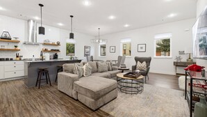 A modern living room with a grey sectional sofa, a coffee table, and a dining area with a bar. - Razorblock North - 1 mi from DT - 3 blocks to UofA (Fayetteville)