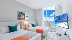 A hotel room with two beds, a TV, and a large window with a city view. - Hide Ocean Resort (Hollywood)