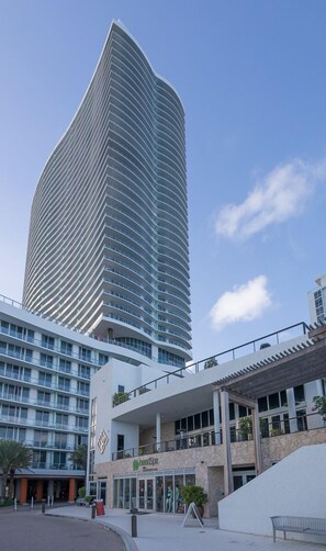 Un hotel moderno con fachada de rascacielos curvo, un spa y un área exterior cubierta.
