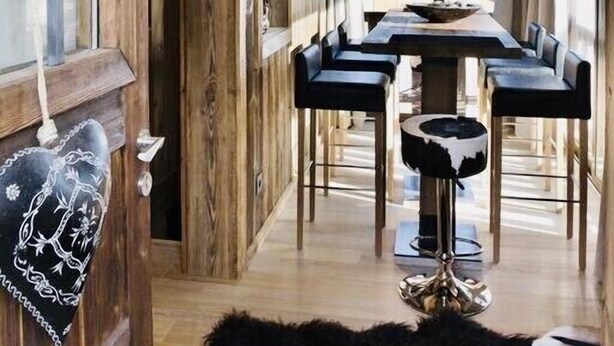 Un intérieur en bois comprenant un coin repas, de grandes fenêtres et un luminaire suspendu.