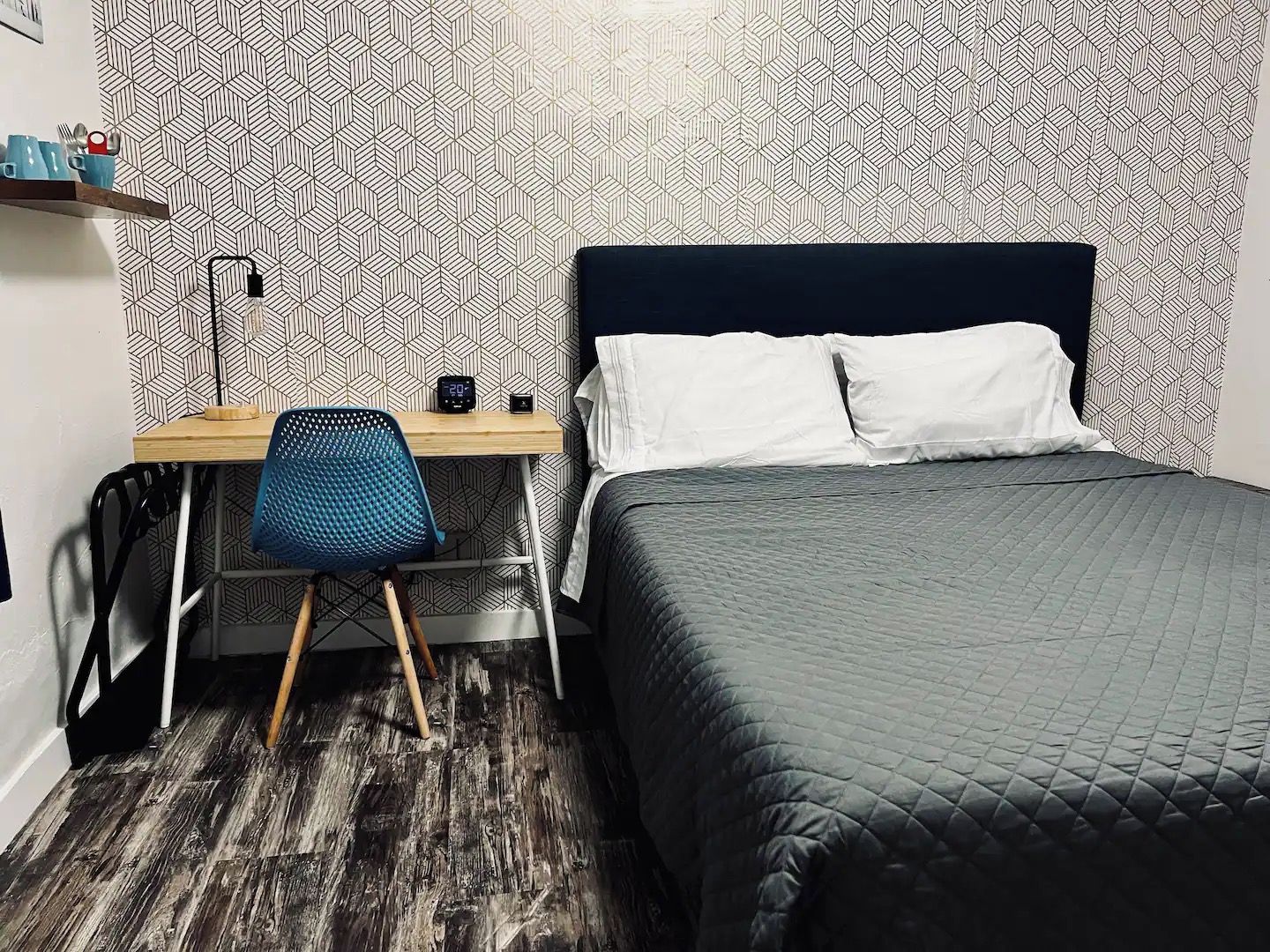 A bedroom with a bed, a desk, and a chair.