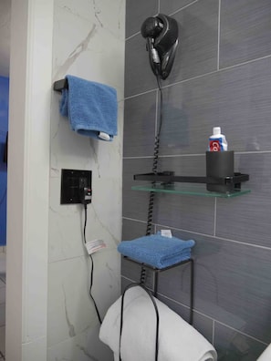 Ein Badezimmer mit Föhn, Handtuchhalter und Ablage für Toilettenartikel.