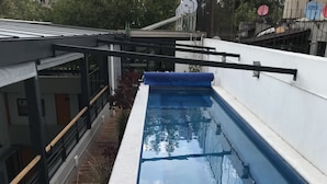 A swimming pool with a clear blue water surface, surrounded by a white pool deck and a wooden deck area. - noox Buenavista (Mexico City)