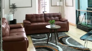 A modern living room with a brown leather sofa, a round coffee table, and a patterned rug.