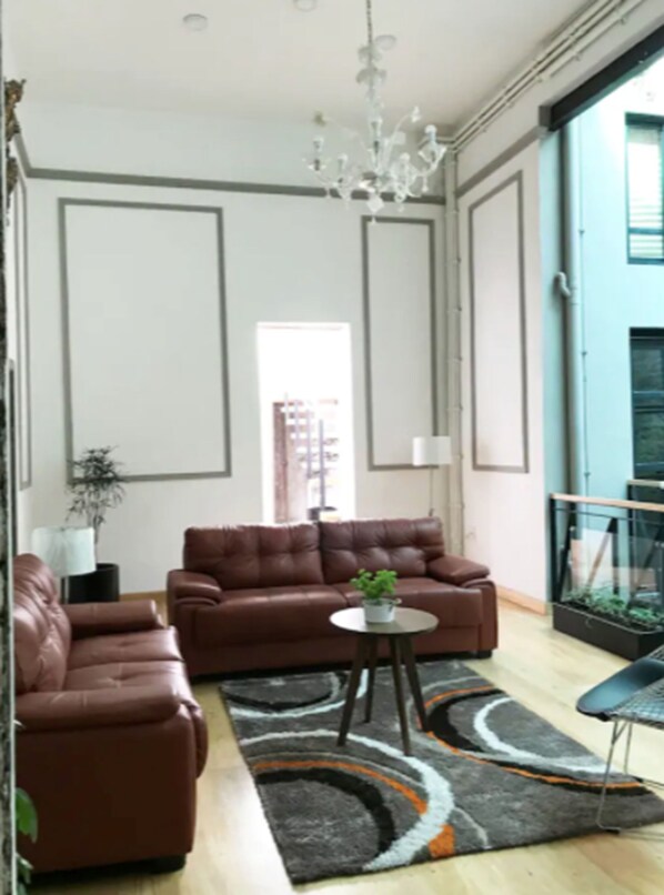 A modern living room with a brown leather sofa, a round coffee table, and a patterned rug.