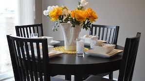 A dining table with a vase of yellow flowers, white plates, and clear glasses. - noox Ayuntamiento (Mexico City)