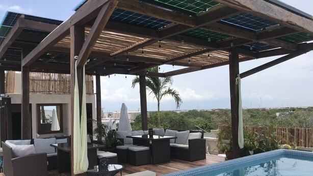 A covered outdoor area with a pool, seating, and a view of the city. - noox Tulum (Tulum)