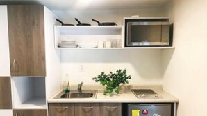 A compact kitchen with a built-in microwave, a sink, and a small refrigerator.