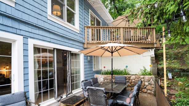 Une terrasse avec une table et des chaises, une plateforme en bois et un mur en pierre.