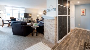 Un salon avec une cheminée, un téléviseur et un coin repas comprenant une table et des chaises.