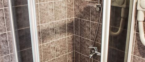 Un box de ducha con paredes de cristal, suelo de azulejos y ducha.