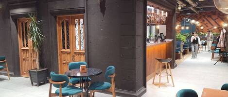 Un interior moderno con una zona de bar, arreglos de asientos y una escalera.