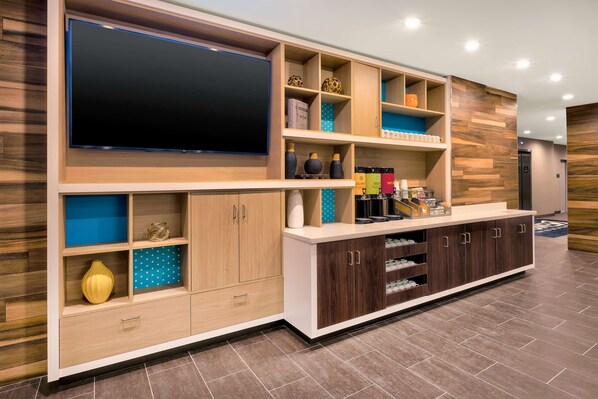 Una sala de estar moderna con un televisor de pantalla plana grande, armarios de madera y estanterías con diversos objetos decorativos.