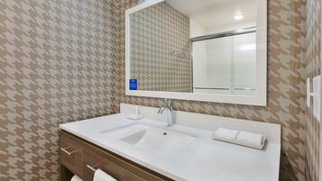 A bathroom with a white sink, a mirror, and patterned wallpaper.