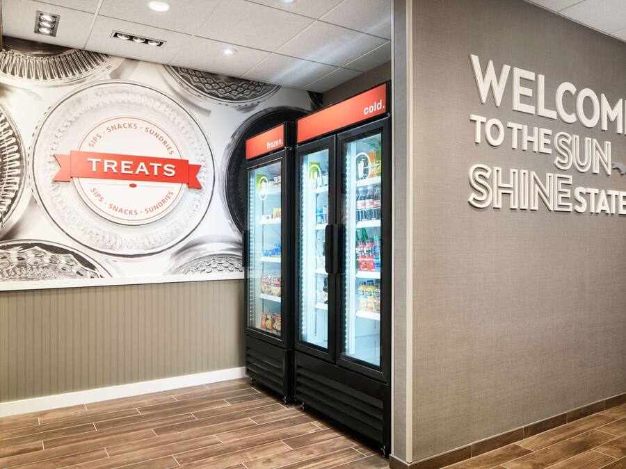 A wall with a "Welcome to the Sun Shine State" sign and a "Treats" sign above two refrigerated display cases.