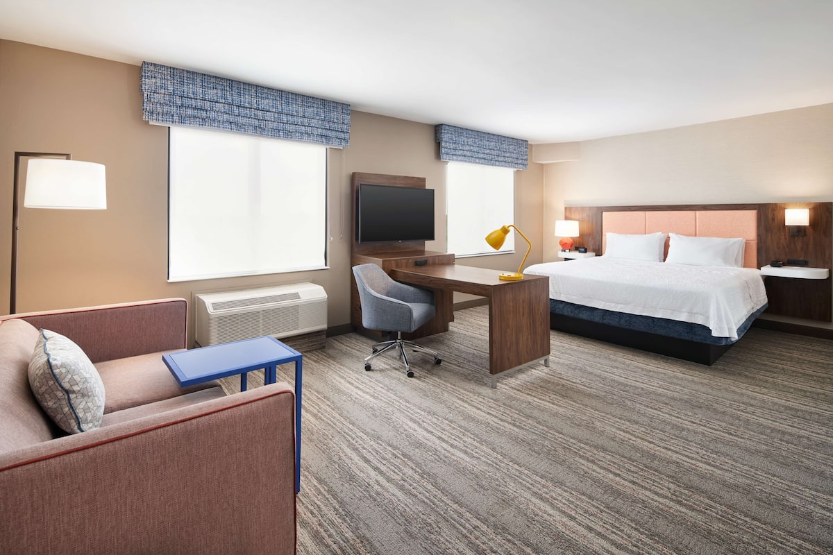 Ein Hotelzimmer mit Bett, Schreibtisch mit Stuhl, Fernseher und Fenster mit Blick.