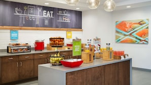 A breakfast bar with a chalkboard menu, a fruit bowl, and a juice dispenser. - Hampton Inn Clewiston (Clewiston)