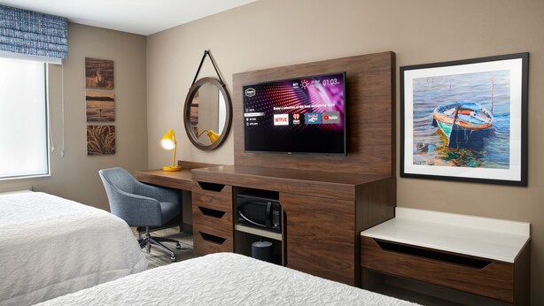 A hotel room with two beds, a desk with a flat-screen TV, a microwave, and a framed painting. - Hampton Inn Clewiston (Clewiston)