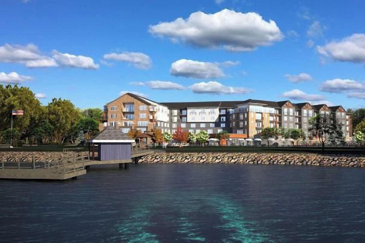 A waterfront hotel with multiple-story buildings, a dock, and a rocky shoreline.