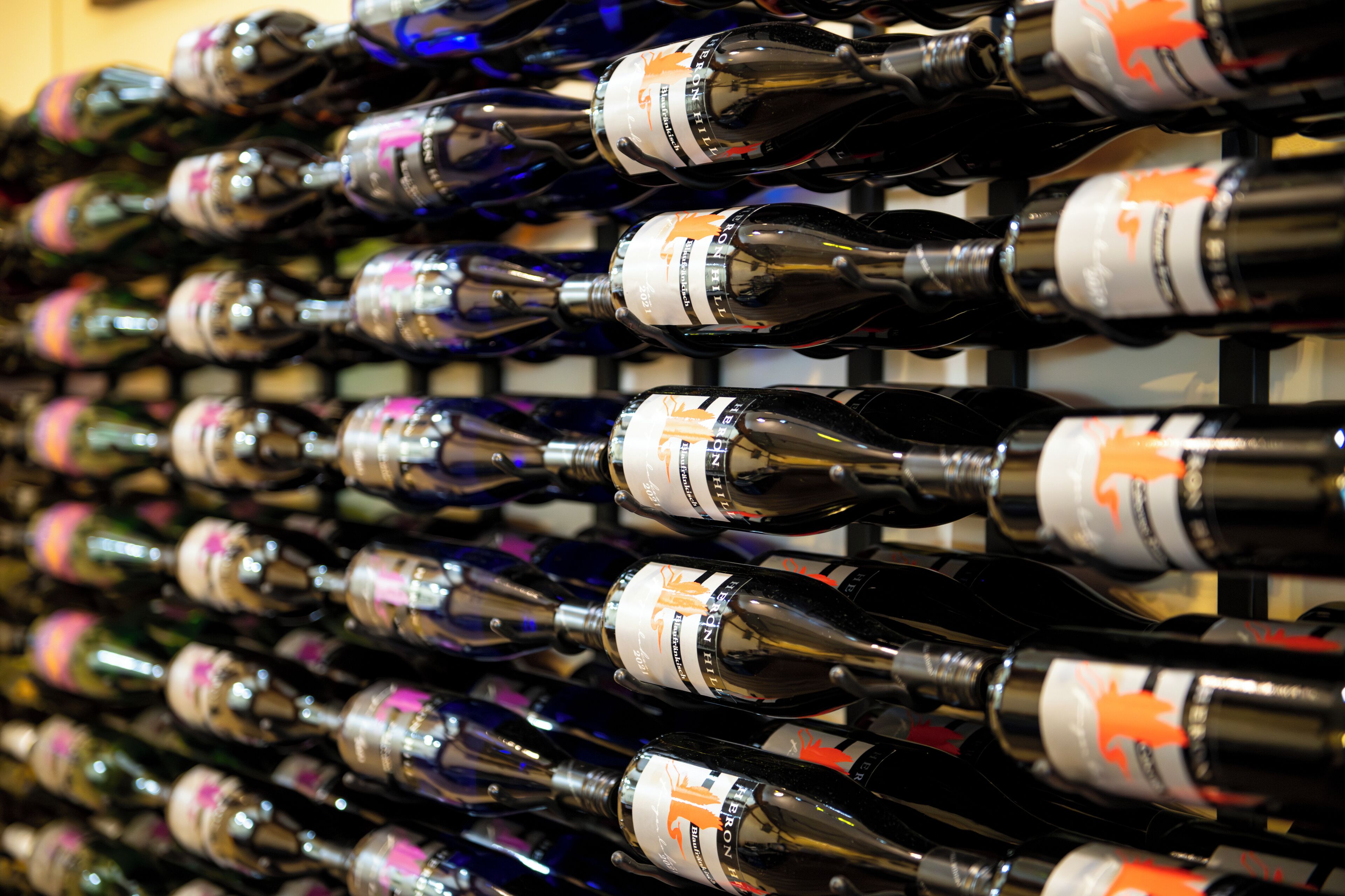 A wall of wine bottles with labels, arranged in rows.