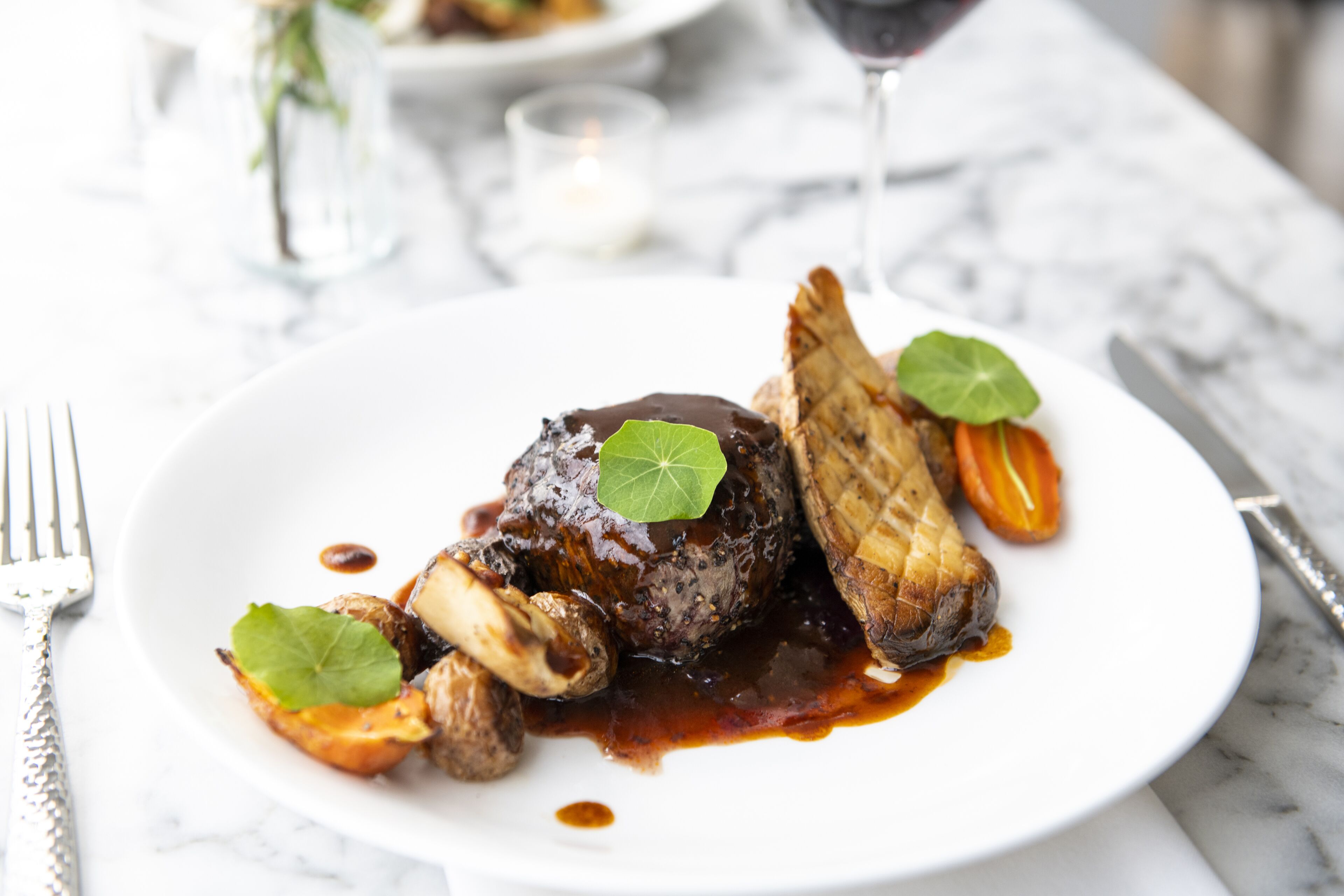 A plate of food with a steak, mushrooms, and vegetables on a white plate.