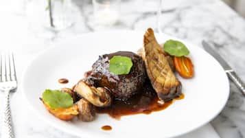 A plate of food with a steak, mushrooms, and vegetables on a white plate.