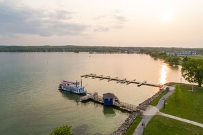 A lake with a dock, a boat, and a small building near the shore. - Hotel Canandaigua, Tapestry Collection by Hilton (Canandaigua)