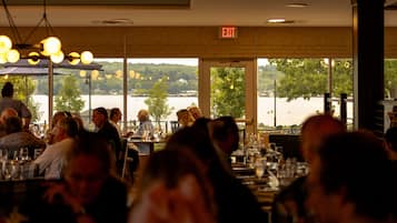 A restaurant with tables and chairs, a view of a lake, and an exit sign.