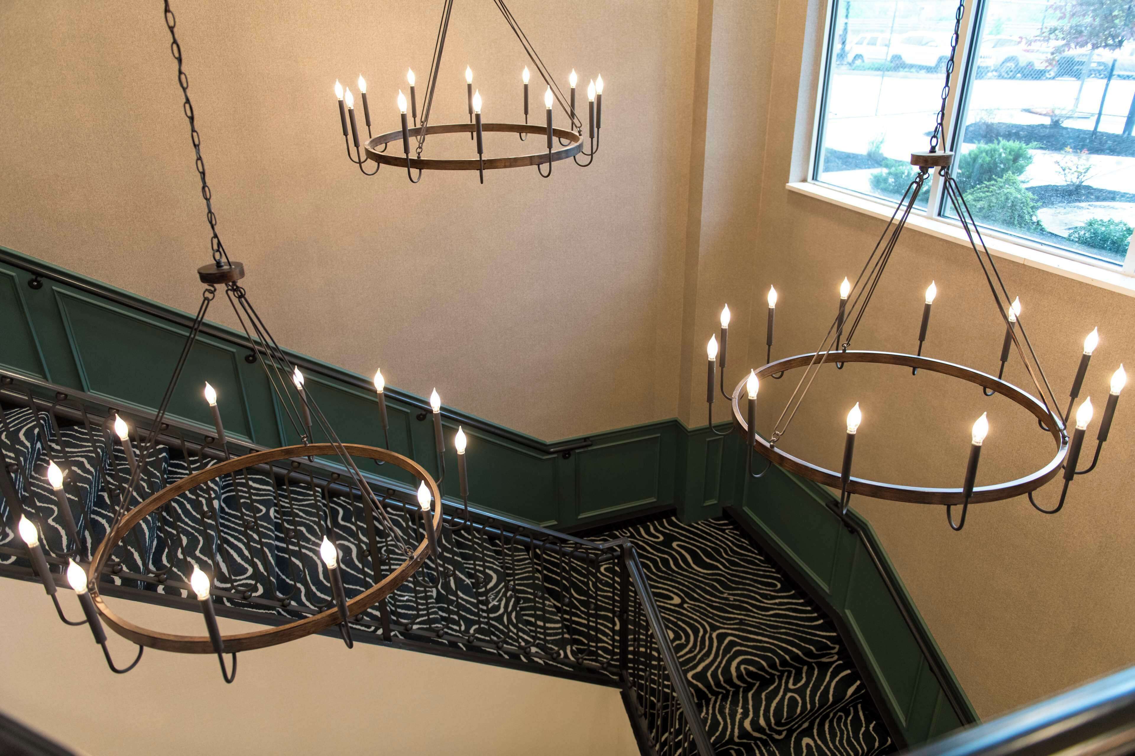 A staircase with a zebra-patterned carpet and two chandeliers with multiple candles.