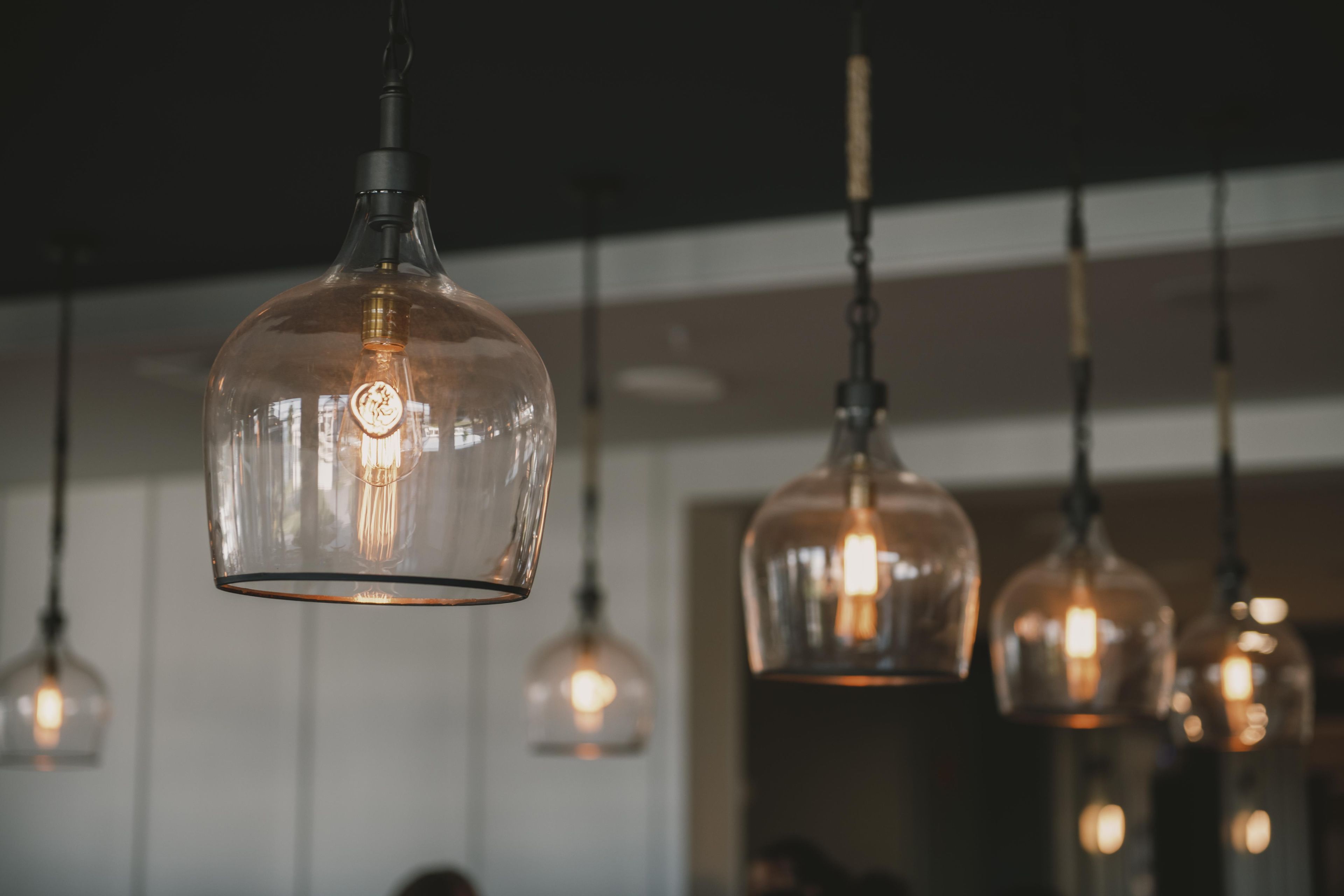 A series of pendant lights with a clear glass shade and visible filament bulbs.