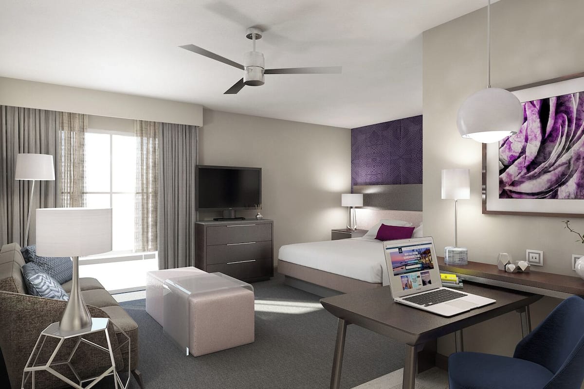 Une chambre d’hôtel moderne équipée d’un lit, d’un bureau et d’un coin salon.