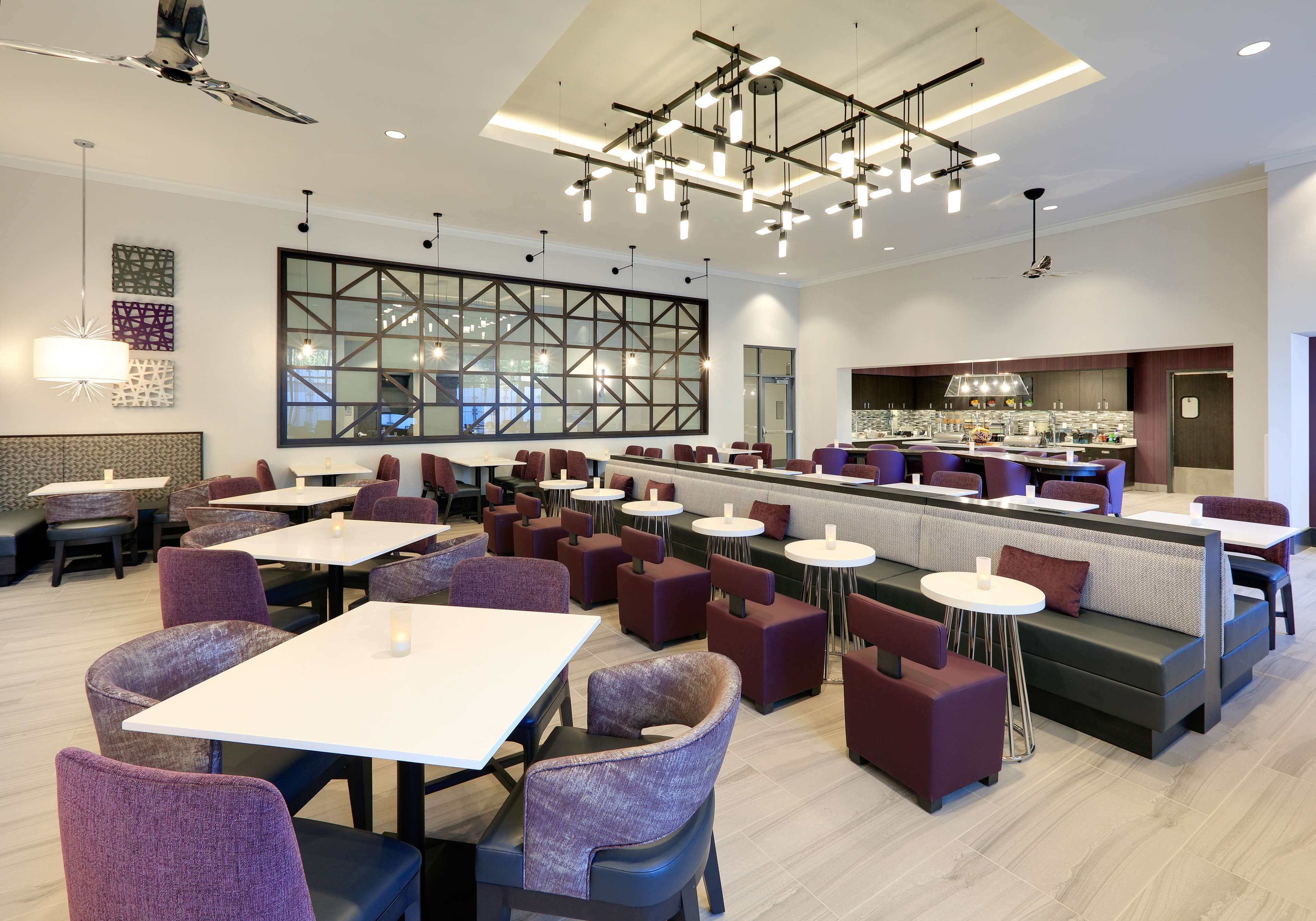 A modern restaurant with multiple seating areas, including tables and booths, and a bar area.
