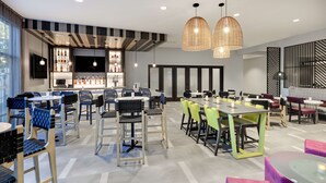 Un restaurant modern amb diverses sales de dinar, incloent una zona de bar amb una varietat de botelles i una televisió de pantalla plana.