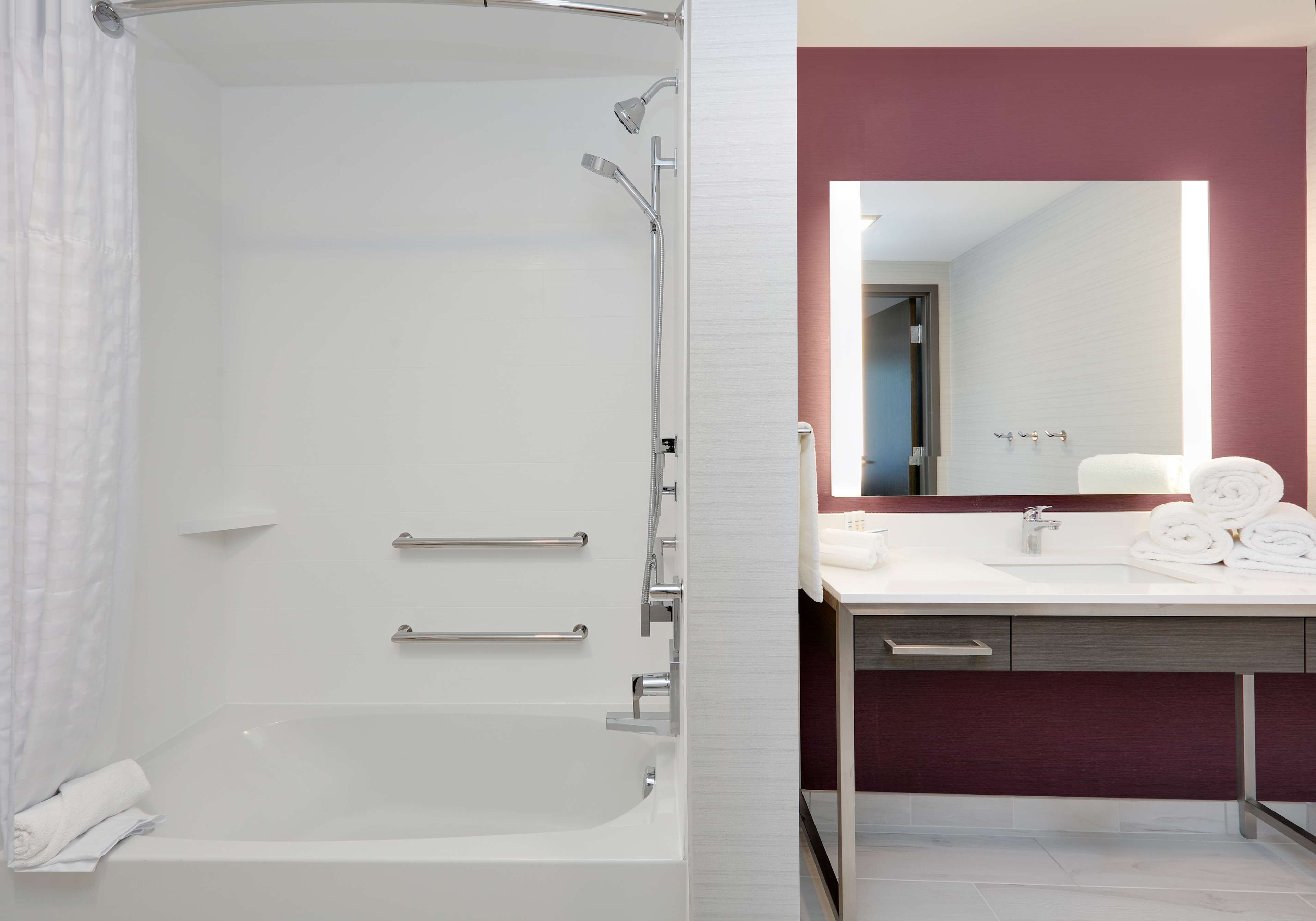 A modern bathroom with a bathtub, shower, and vanity with a mirror.