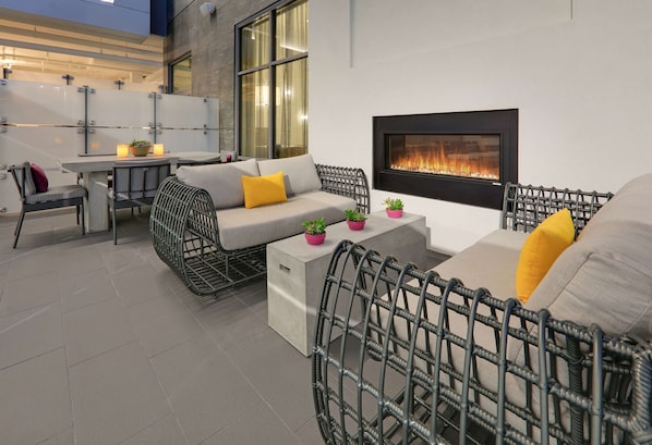 Un espacio al aire libre con mobiliario de mimbre, una mesa y una chimenea.