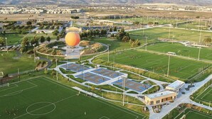 Vista aèria d'un complex esportiu amb diverses pistes, una estructura esfèrica gran i un edifici amb teulada plana.