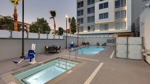 An indoor swimming pool area with two pools, lounge chairs, and a building with multiple windows in the background. - Hampton Inn by Hilton Irvine Spectrum/Lake Forest (Lake Forest)