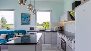 Una cocina moderna con una isla central, electrodomésticos de acero inoxidable y vistas a zonas verdes.