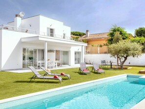 Uma casa moderna com piscina, área de estar externa e um gramado bem cuidado.