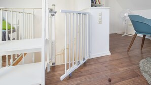 Une pièce avec un berceau blanc, une armoire blanche et une chaise bleue.