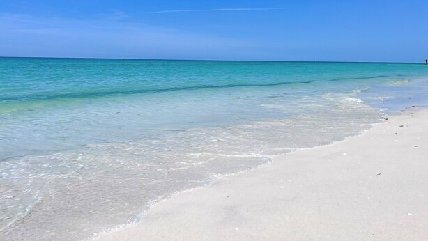 Uma praia com águas azul-turquesa cristalinas e areia branca.