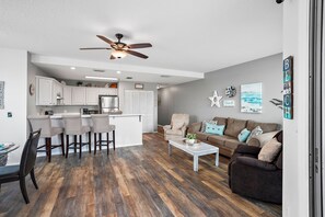 Un salon moderne comprenant un coin repas, une cuisine et un ventilateur de plafond.