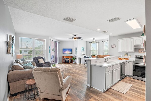 A modern kitchen with white cabinets, a central island, and a dining area with a table and chairs.