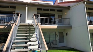 A two-story building with a central staircase, a balcony on the upper floor, and a door with a small window. - Newly Renovated! CB Condo unit 104 (sleeps up to 8) (Quincy)