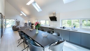 Una cocina moderna con una isla grande, electrodomésticos integrados y abundante luz natural proveniente de tragaluces.