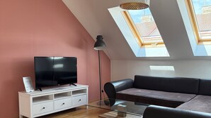 En moderne stue med TV, sofa og sofabord i glas.