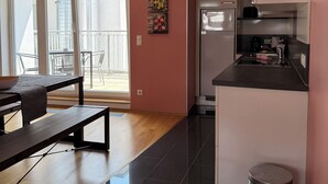 Et moderne køkken med køleskab, komfur og vask. Der er et spiseområde med bænk og bord, og en balkon med stole.