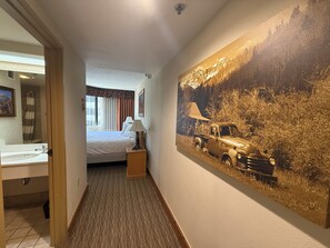 Ein Hotelzimmer mit Bett, Badezimmer mit Waschbecken und einem großen Gemälde eines Lastwagens an der Wand.